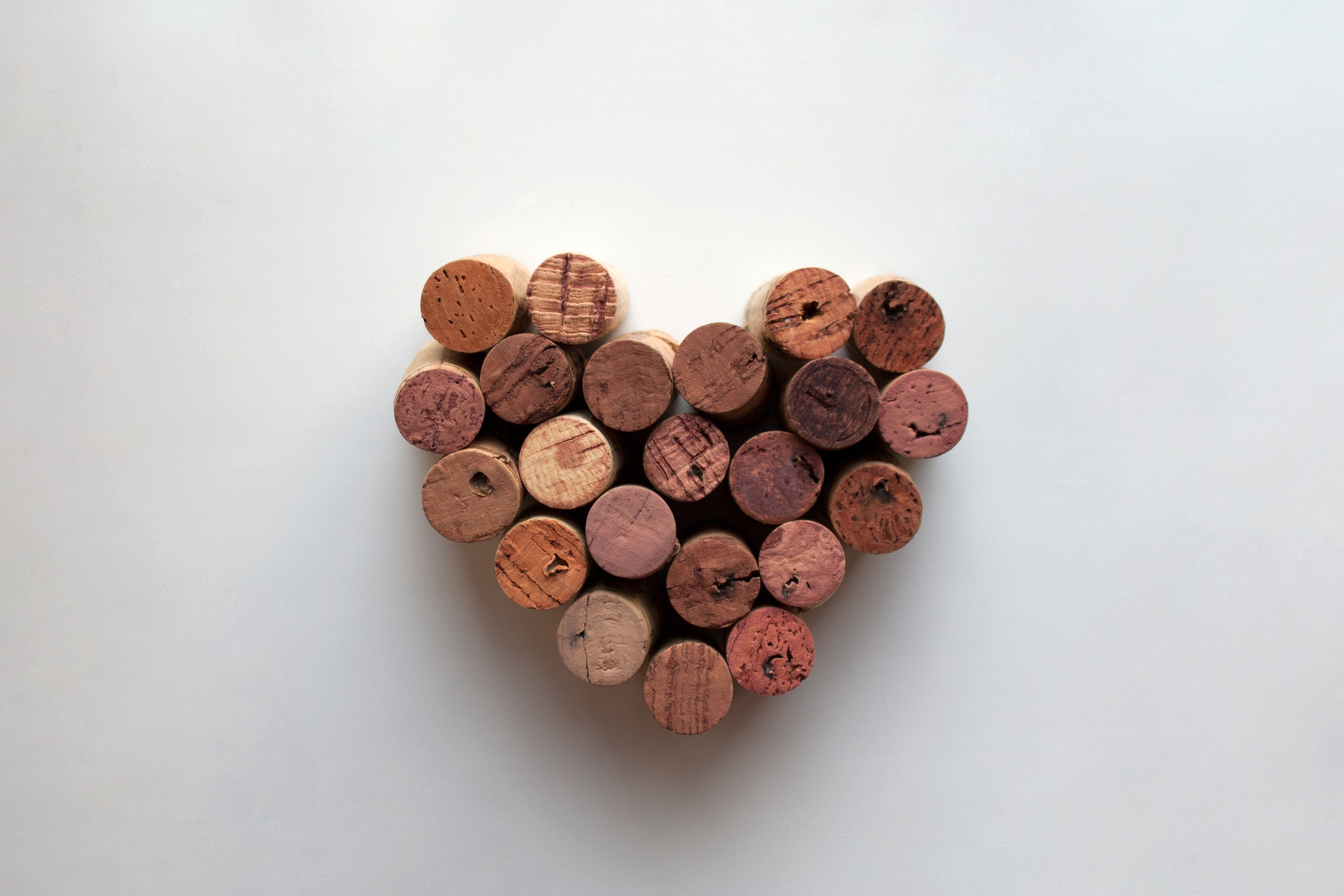 Heart-shaped arrangement of natural wine corks on a white background, symbolizing love for wine.