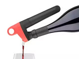 Wine bottle pouring device with a red and black design, dispensing red wine into a glass.