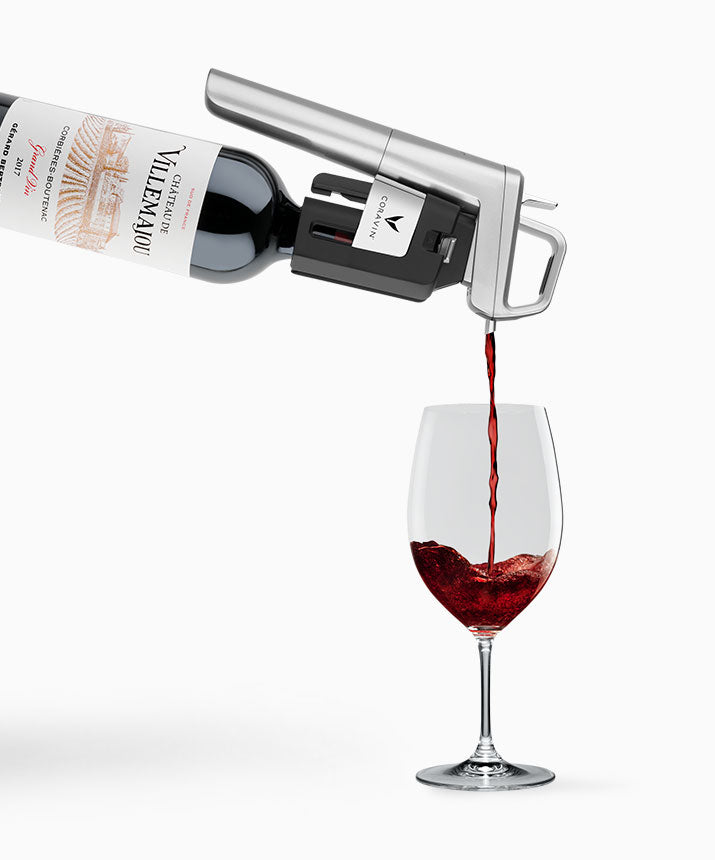 Red wine being poured from a bottle into a wine glass, featuring the label "Château de Villemajou."