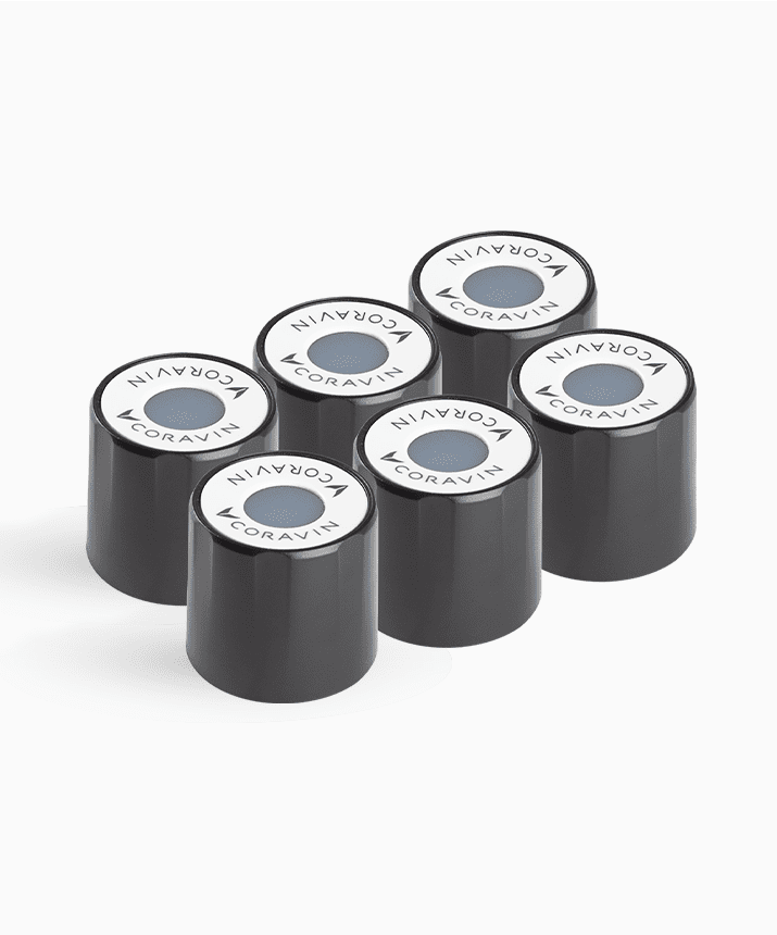 Six black Coravin capsules stacked, each featuring a round white top with the Coravin logo and a colored dot in the center.