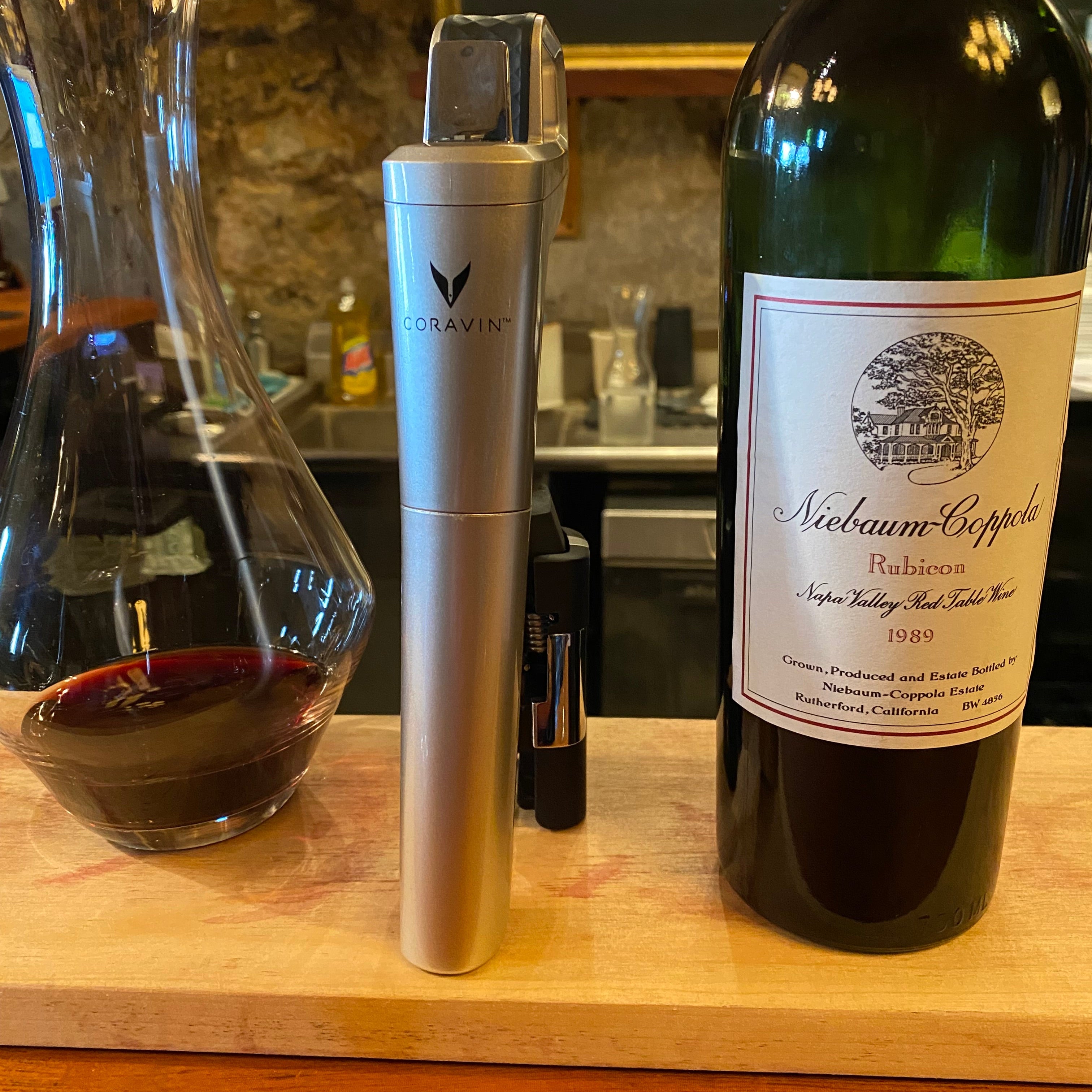 Coravin wine preservation system next to a decanter and bottle of Niebaum-Coppola Rubicon 1989 Napa Valley red wine.