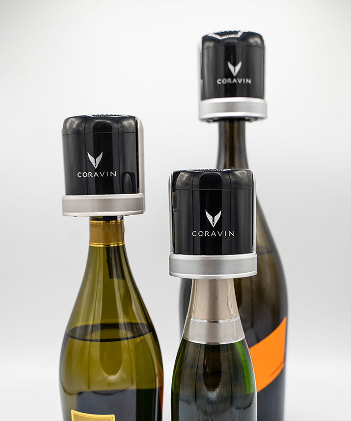 Three wine bottles topped with black Coravin wine preservation systems, showcasing modern wine preservation technology.